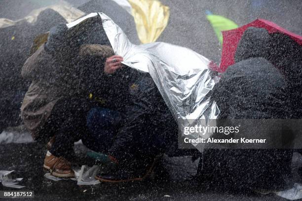 Left-wing protesters get sprayed by a water cannon as they clash with police forces outside the Hannover Congress Centrum prior to today's AfD...