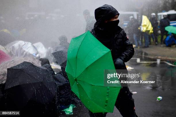 Left-wing protesters get sprayed by a water cannon as they clash with police forces outside the Hannover Congress Centrum prior to today's AfD...