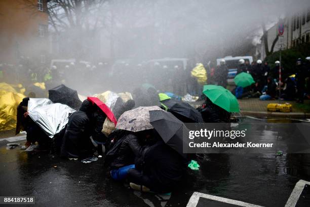 Left-wing protesters get sprayed by a water cannon as they clash with police forces outside the Hannover Congress Centrum prior to today's AfD...