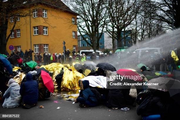 Left-wing protesters get sprayed by a water cannon as they clash with police forces outside the Hannover Congress Centrum prior to today's AfD...