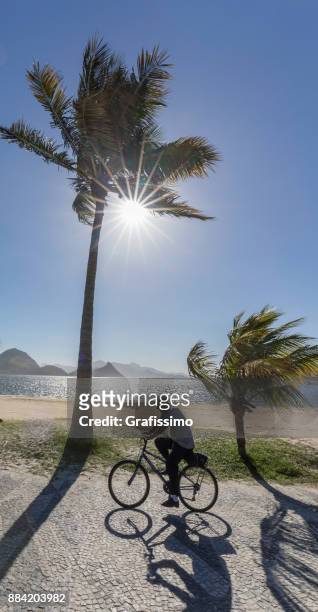 brazilian man on bicycle near the icarai beach on niteroi rio de janeiro - niteroi stock pictures, royalty-free photos & images