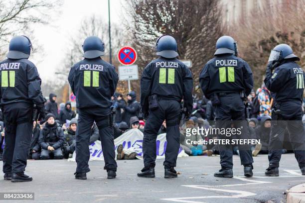 German riot policemen stand guard in front of protesters who take part in a sit-in against the Alternative for Germany far-right party during the...