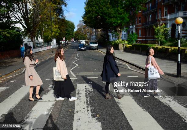 Chinese tourists walk across Abby Road in London, England, recreating the famous 1969 Beatles 'Abby Road' album cover photograph showing the four...