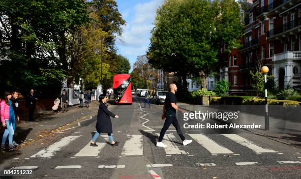 Beatles fans walk across Abby Road in London, England, recreating the famous 1969 Beatles 'Abby Road' album cover photograph showing the four...