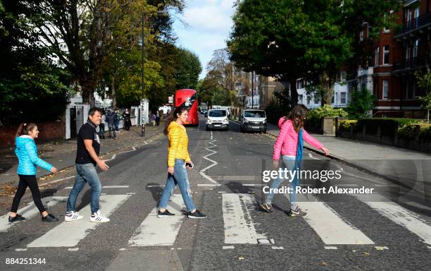 Beatles fans walk across Abby Road in London, England, recreating the famous 1969 Beatles 'Abby Road' album cover photograph showing the four...