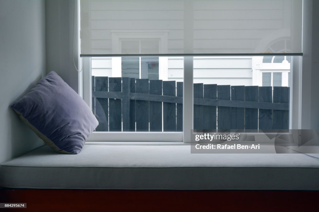 Purple pillow on an empty window bench