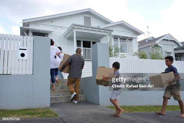 family carries moving boxes into their new home - nz house and driveway stock-fotos und bilder