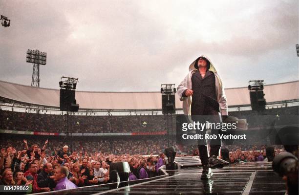 Photo of BONO and U2, Bono performing live on stage at the Feyenoord Stadium during the PopMart tour showing stadium and crowds behind