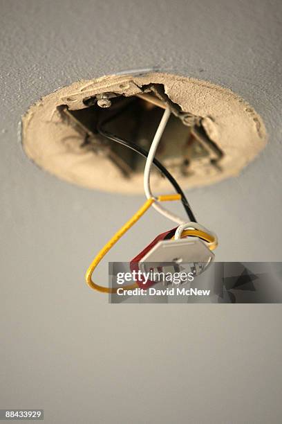 Wires hang from a faulty electrical unit in the ceiling of the apartment of Lisette Guevara who, along with her children, Iliana, 3 months, and Angel...