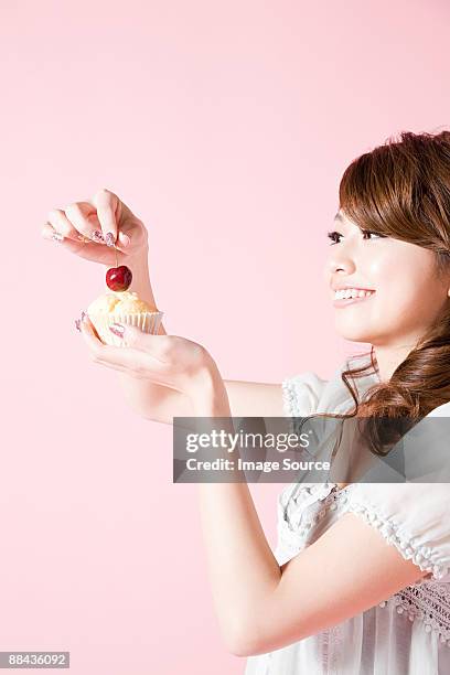 woman putting cherry on cake - cherry on the cake stock pictures, royalty-free photos & images