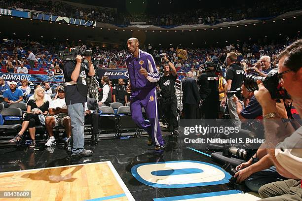 Kobe Bryant of the Los Angeles Lakers runs onto the court as golfer Tiger Woods sits with his wife Elin prior to the Lakers player against the...