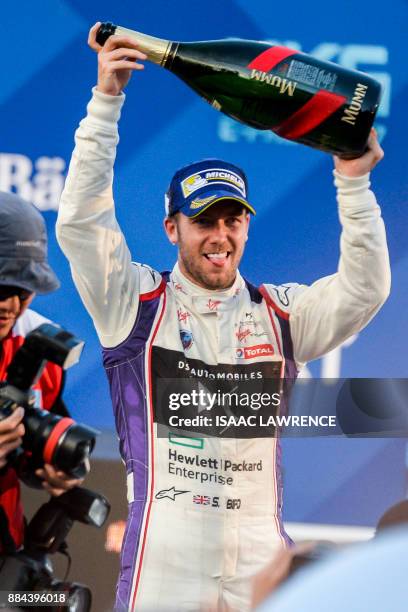 Virgin team driver Sam Bird of Britian holds up a bottle of champagne to celebrate after winning the Formula E motor racing championship in Hong Kong...