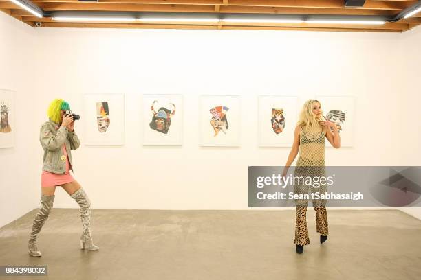 Musician Danke Sound photographs artist Natalie Bergman in front of her artowrk at OptiMystic: A Brandon Boyd Pop Up Gallery Featuring He, Tasya Van...