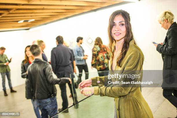 Artist Diana Garcia poses for a photo in front of her artwork at OptiMystic: A Brandon Boyd Pop Up Gallery Featuring He, Tasya Van Ree, Natalie...