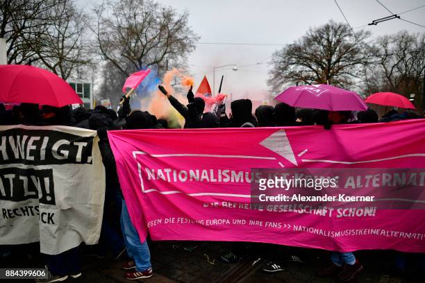 Left-wing protesters burn colour flares during a protest march during todays AfD federal congress at the Hannover Congress Centrum on December 2,...