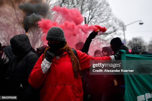 Left-wing protester holds a banner while others burn colour flares during a protest march during todays AfD federal congress at the Hannover Congress...