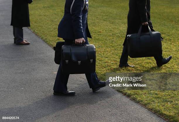 Military aide carries the nuclear football as he walks toward Marine One to depart with U.S. President Donald Trump., on December 2, 2017 in...