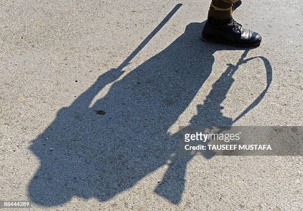 The shadow of an Indian paramilitary troopers falls as he stands guard at a road block to prevent anti-Indian protests over the alleged rape and...