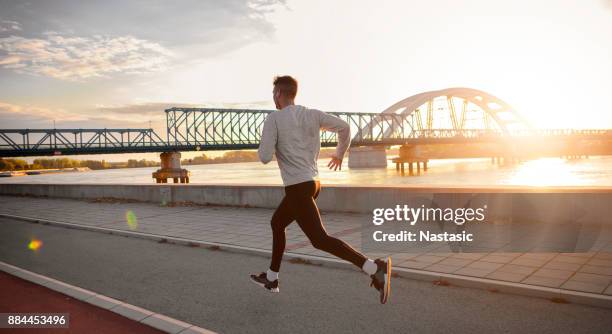 city-läufer gegen sonnenaufgang sonne - running in the sun stock-fotos und bilder