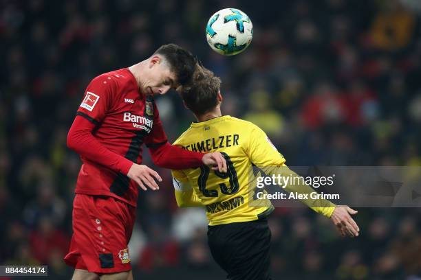 Kai Havertz of Leverkusen jumps for a header with Marcel Schmelzer of Dortmund and hits the cross bar during the Bundesliga match between Bayer 04...