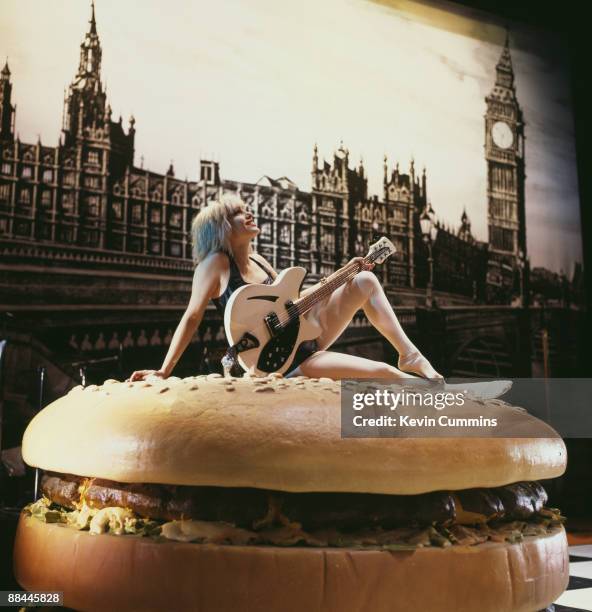 American guitarist Brix Smith, of rock group The Fall, poses on a giant hamburger from the set of the ballet 'I Am Kurious Oranj', performed by...