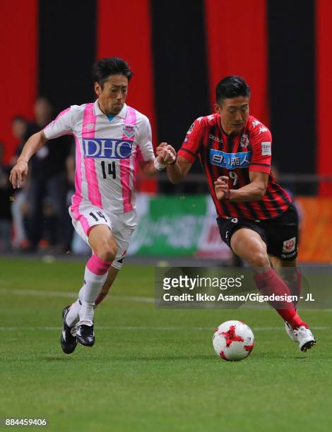 Ken Tokura of Consadole Sapporo and Yoshiki Takahashi of Sagan Tosu compete for the ball during the J.League J1 match between Consadole Sapporo and...