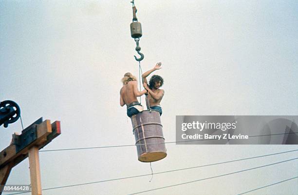 Two unidentified, shirtless men are lifted in a barrel by a crane at the Woodstock Music and Arts Fair in Bethel, New York, August 15 - 17 , 1969.