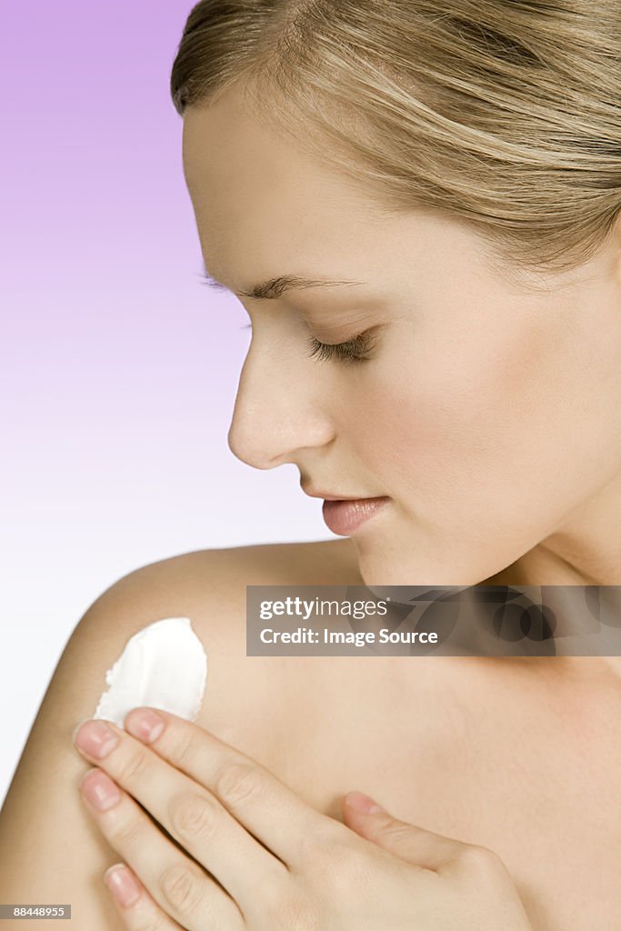 Woman applying body lotion