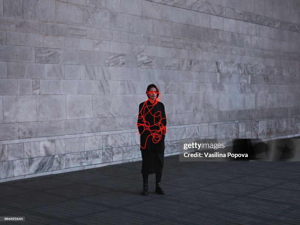 Woman entangled with neon wires against urban marble background