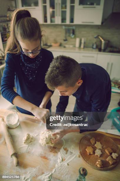 familie lustig kinder backen kekse in küche - bruder schwester kochen stock-fotos und bilder