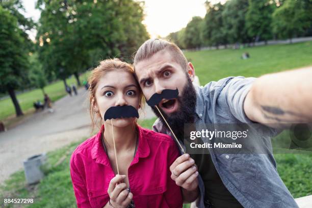 jugendliche machen selfie mit papier schnurrbärte - movember stock-fotos und bilder