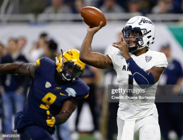 Quarterback Kato Nelson of the Akron Zips passes the ball as defensive end Olasunkanmi Adeniyi of the Toledo Rockets closes in during the first half...