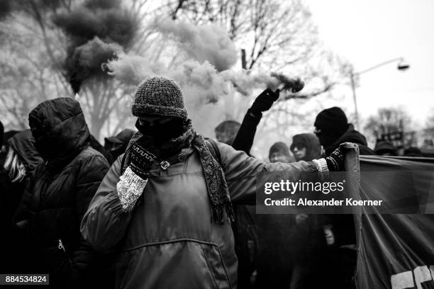 Left-wing protester holds a banner while others burn colour flares during a protest march during todays AfD federal congress at the Hannover Congress...