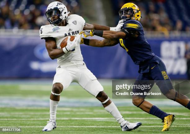 Wide receiver Tra'Von Chapman of the Akron Zips stiff-arms cornerback Josh Teachey of the Toledo Rockets while carrying the ball during the first...