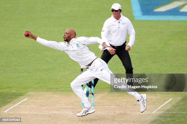 Kieran Powell of the West Indies fields off his own bowling while umpire Rod Tucker of Australia looks on during day three of the Test match series...