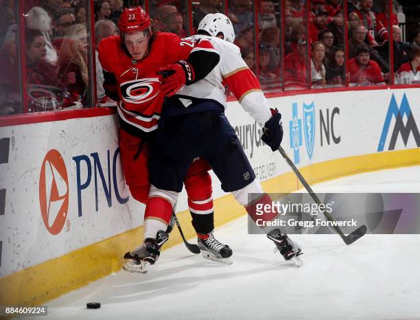 Brock McGinn of the Carolina Hurricanes and Ian McCoshen of the Florida Panthers battle along the boards during an NHL game on December 2, 2017 at...