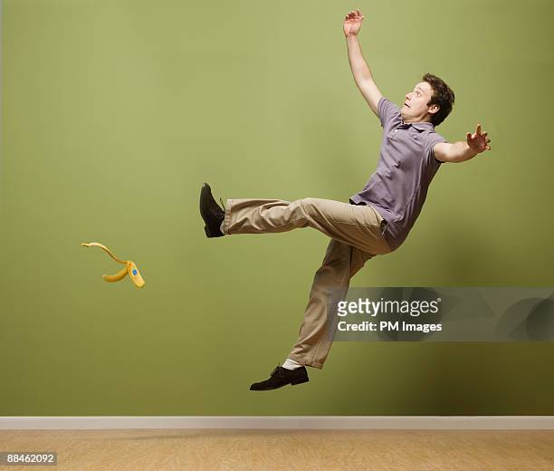 man slipping on banana peel - fallen stockfoto's en -beelden