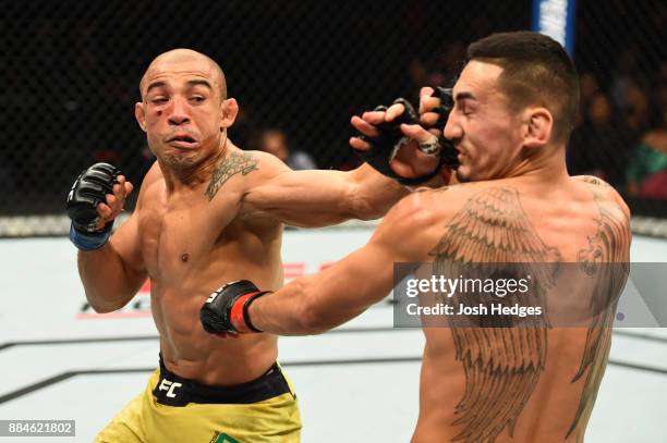 Jose Aldo of Brazil punches Max Holloway in their UFC featherweight championship bout during the UFC 218 event inside Little Caesars Arena on...