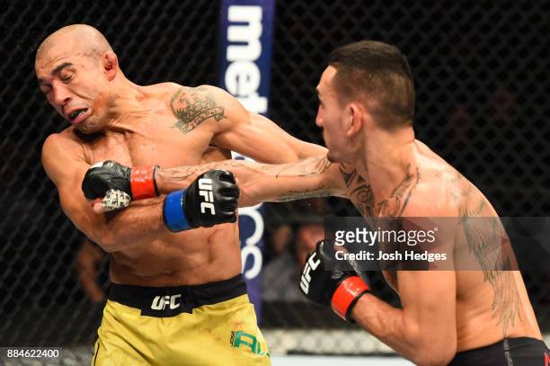 Max Holloway punches Jose Aldo of Brazil in their UFC featherweight championship bout during the UFC 218 event inside Little Caesars Arena on...