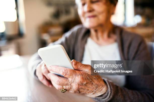 grandmother at home using smart phone. - grandmother stock-fotos und bilder