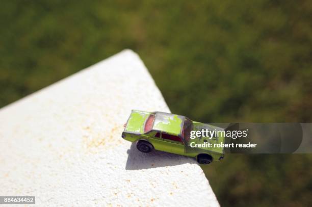 green toy car hanging over edge of a wall - broken toy stock pictures, royalty-free photos & images