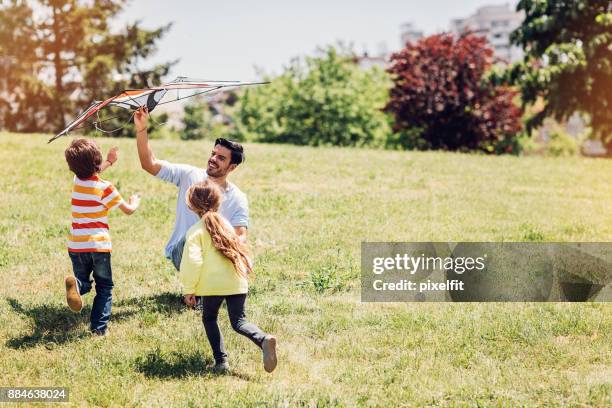 father playing with children - kite flying stock pictures, royalty-free photos & images