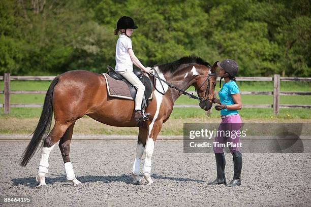young girl on horseback with riding instructor. - reins stock pictures, royalty-free photos & images