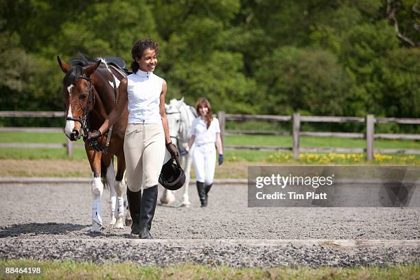 two female horse riders leaving a riding arena. - recreational horseback riding stock pictures, royalty-free photos & images