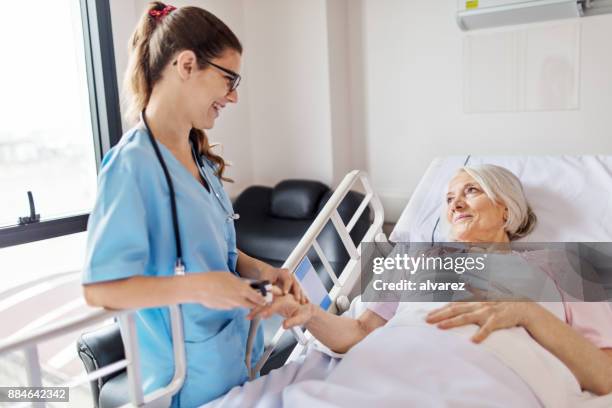 verpleegkundige aanpassen oxymeter op senior vrouw vinger - female nurse stockfoto's en -beelden