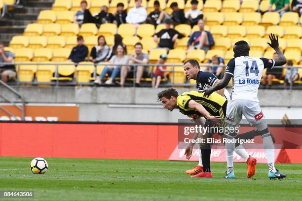 Matthew Ridenton of the Wellington Phoenix tries to get past Thomas Deng and Leigh Broxham of Melbourne Victory during the round nine A-League match...