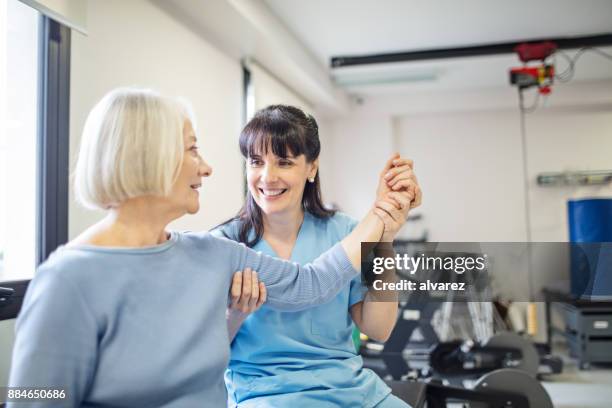 enfermera asistencia a mujer senior con ejercicio de mano - orthopedics fotografías e imágenes de stock