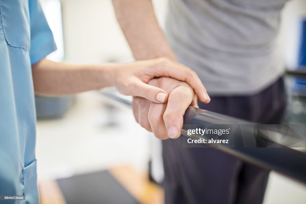 Infermiera donna che tocca la mano dell'uomo anziano sulla ringhiera