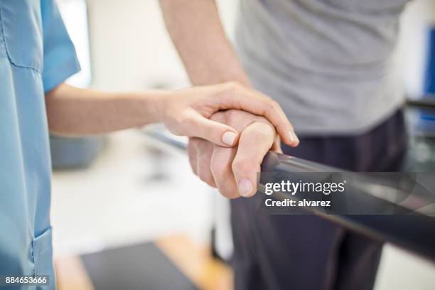 vrouwelijke verpleegkundige aanraken van senior iemands hand op leuning - afkickcentrum stockfoto's en -beelden