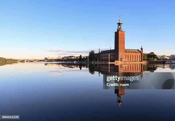 rathaus von stockholm mit reflektion auf ruhigem wasser - stockholm summer stock-fotos und bilder